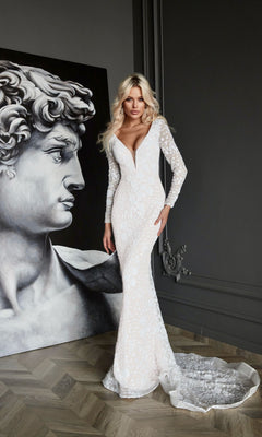 A woman in a fitted Long Formal Dress: Tina Holly BB023 stands indoors next to a large black-and-white portrait of Michelangelo’s David.