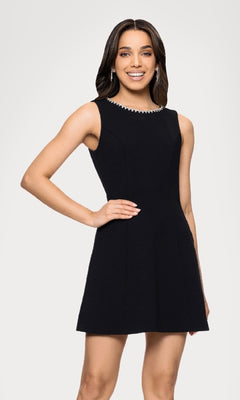 A woman smiles at the camera against a plain light background, wearing the Blondie Nites BC164 Black Cut-Out Mini Hoco Dress with a decorative neckline.