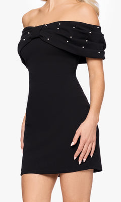 Woman in the Off-Shoulder Black Hoco Dress: Blondie Nites BC174, featuring a front bow and pearl-beaded neckline—an ideal short black party or homecoming dress.