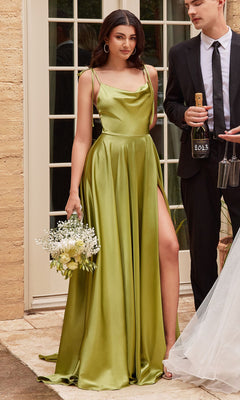 A woman in the Cowl-Neck Long Satin Prom Dress: Ladivine BD104 with a thigh-high slit holds a bouquet, standing beside a man in a black suit holding a wine bottle and glasses.