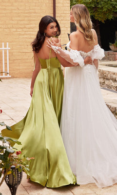 Two women stand outdoors, one wearing the Ladivine BD104 Cowl-Neck Long Satin Prom Dress and the other in a white off-the-shoulder gown, holding hands and looking back over their shoulders.