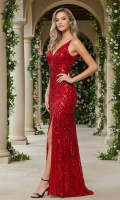 A woman wears the Blondie Nites 5415BN long prom dress with red sequins and a thigh-high slit, standing on a garden walkway bordered by stone columns and greenery.