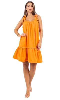 A woman models the Short Casual Smock Dress with Shoulder Ties in orange, featuring an oversized fit, ruffle hem, and tied straps. She stands against a white background, showcasing this effortlessly stylish dress.