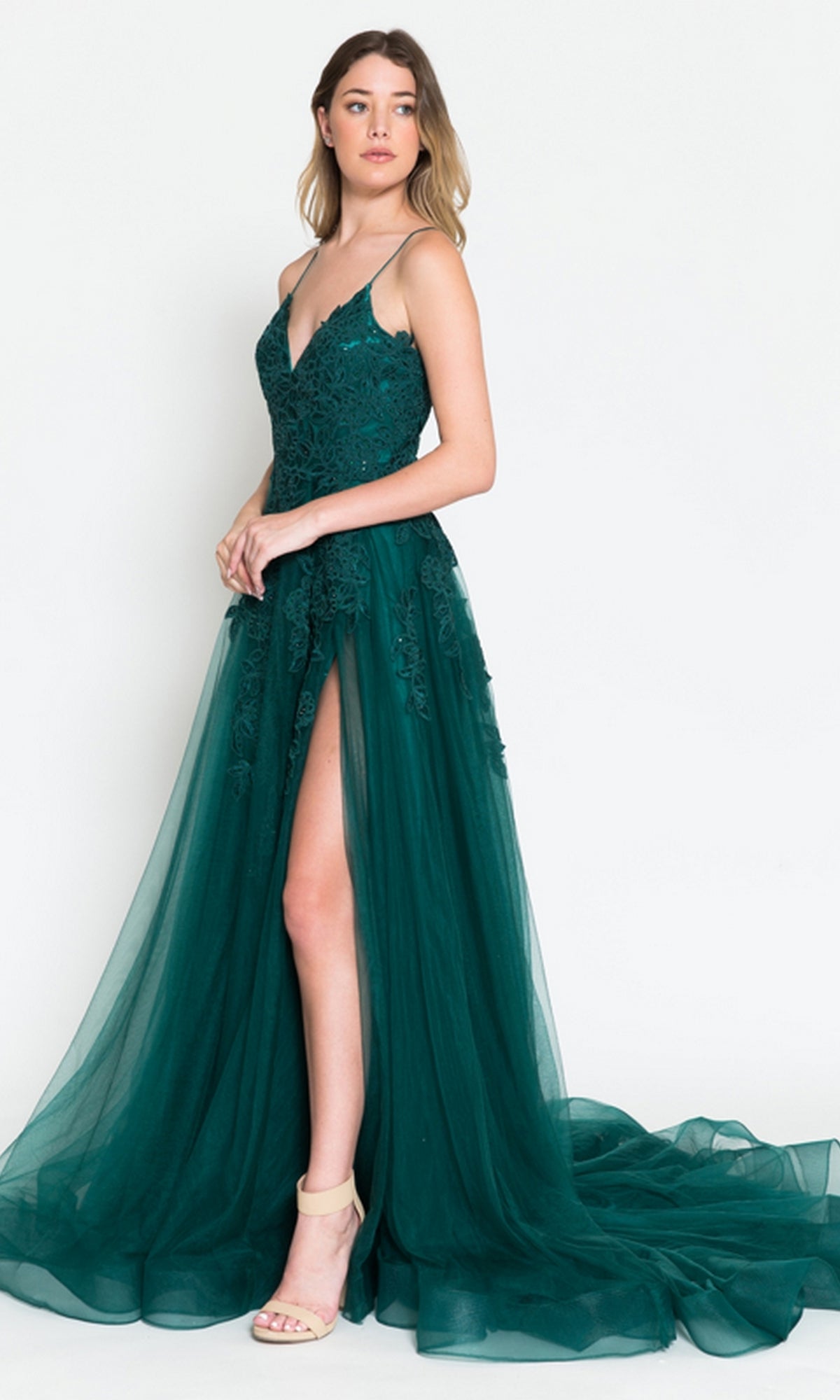 A woman models the Long Tulle Prom Ball Gown with Train BZ014 in deep green, featuring an embroidered floral lace bodice, sheer skirt, and high slit, standing against a plain white background.