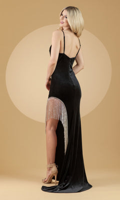 A woman stands on a beige background wearing the Amelia Couture Black Designer Prom Dress BZ9015V with silver detailing, high slit, and nude high-heeled sandals.