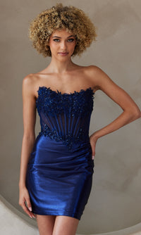 Woman wearing a navy blue strapless short dress standing in front of a neutral background