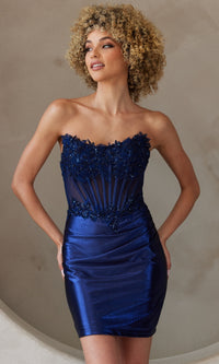 Woman wearing a strapless short navy blue dress with beaded corset top against a neutral background