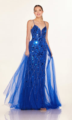 A woman poses against a plain light background in the Long Prom Dress: Cecilia Couture C132—a floor-length, sleeveless blue gown featuring sequin embellishments and a tulle overskirt.