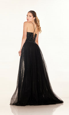 A woman with long hair in a ponytail models the Cecilia Couture C132, a floor-length black prom dress with thin straps, fitted bodice, and lace-up back, standing slightly turned to showcase the design.