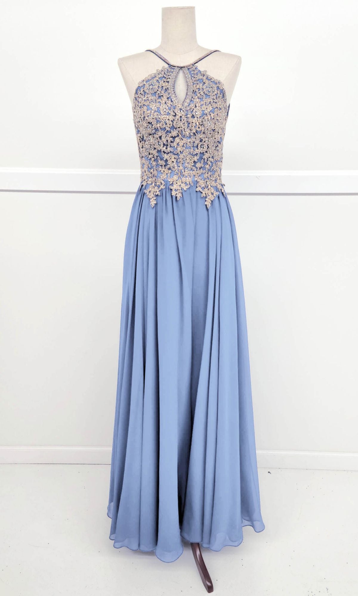 The Chicas C1521 High-Neck Long A-Line Prom Dress features a lavender hue, halter neckline with keyhole cutout, and golden lace embroidered bodice, shown on a dress form against a plain white background.