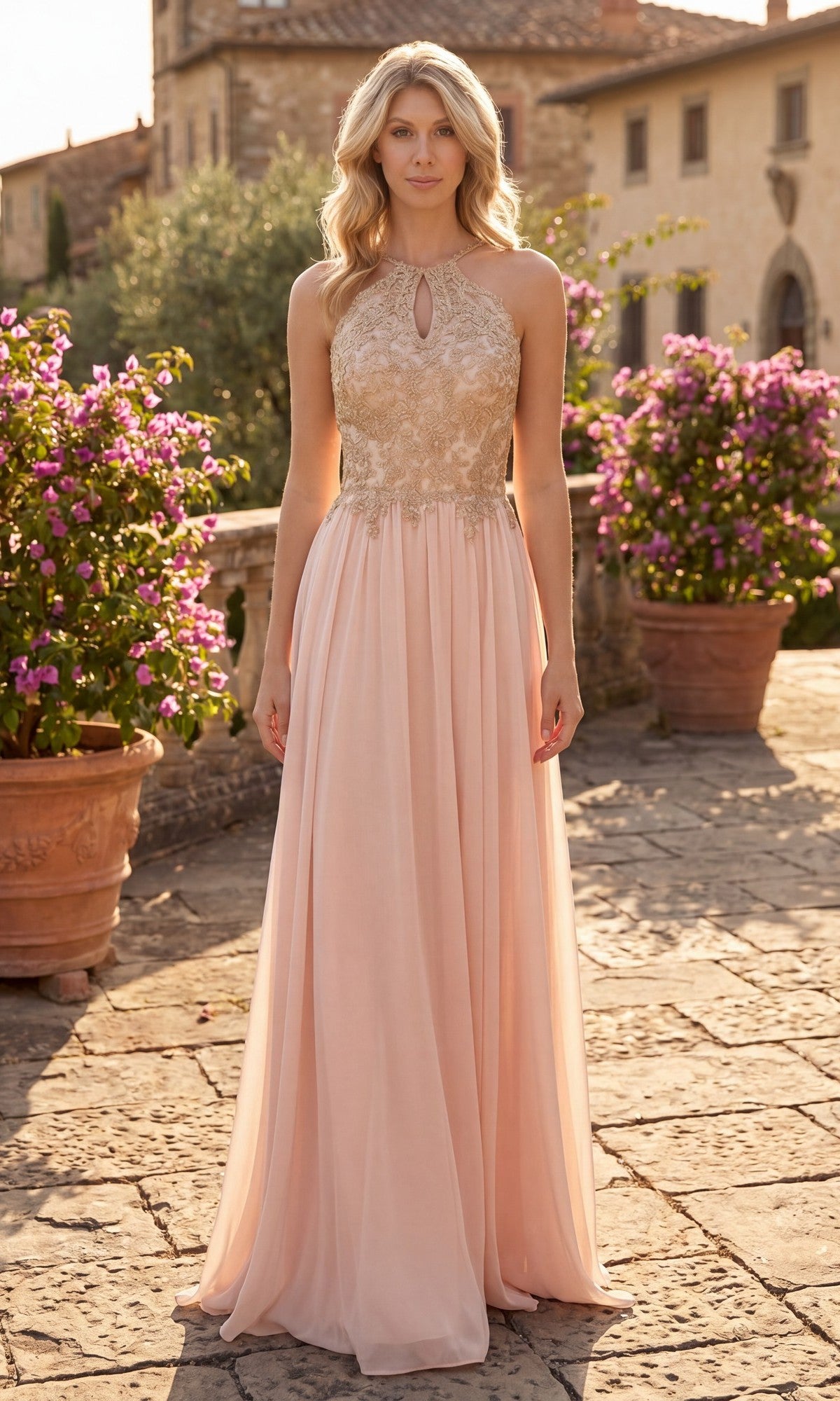 A woman stands outdoors in sunlight, wearing the High-Neck Long A-Line Prom Dress: Chicas C1521—a floor-length, sleeveless, light pink formal gown featuring a gold embroidered lace bodice and a keyhole neckline. Stone pavement and flowering bushes can be seen in the background.