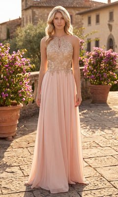 A woman stands outdoors in sunlight, wearing the High-Neck Long A-Line Prom Dress: Chicas C1521—a floor-length, sleeveless, light pink formal gown featuring a gold embroidered lace bodice and a keyhole neckline. Stone pavement and flowering bushes can be seen in the background.