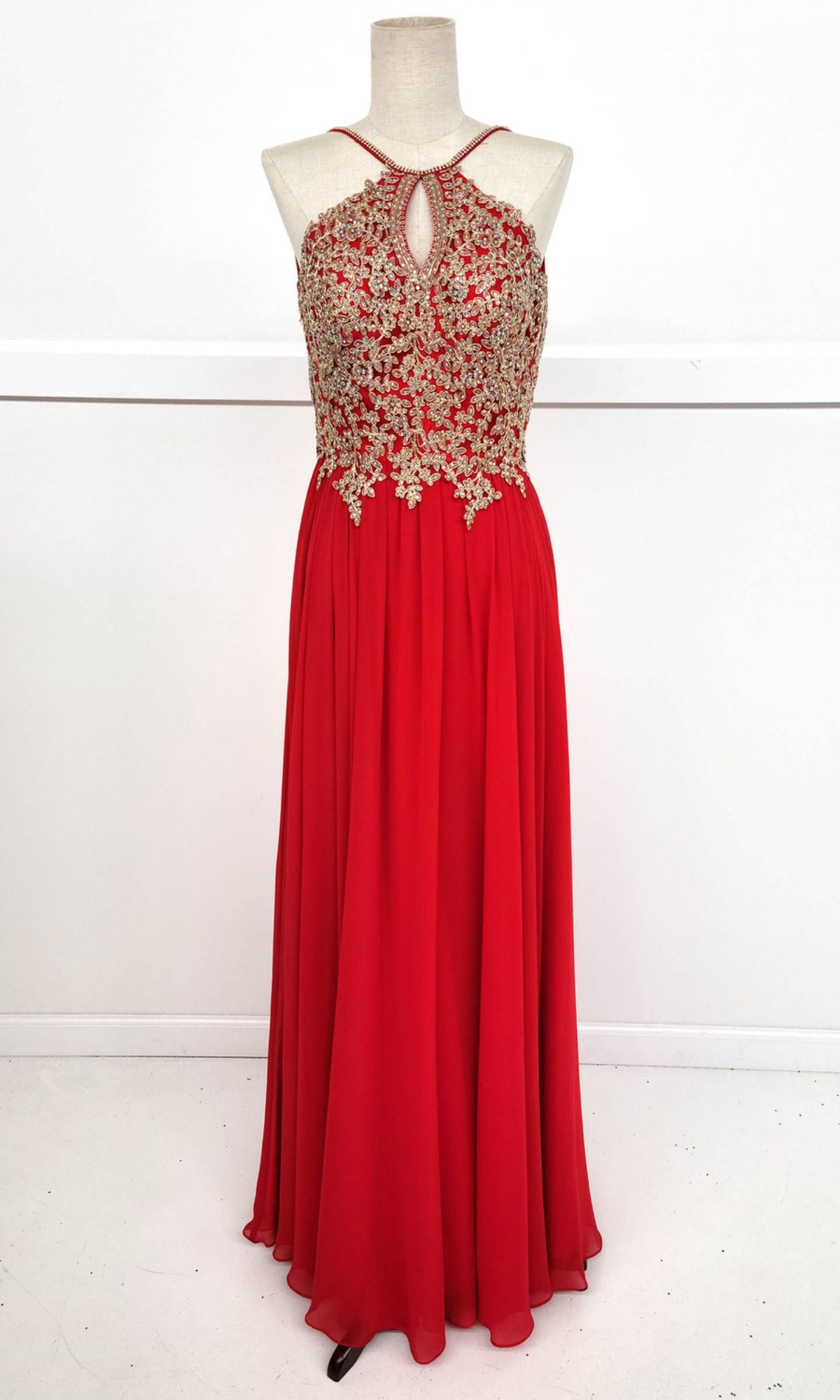 The Chicas C1521 High-Neck Long A-Line Prom Dress is sleeveless, red, features a keyhole neckline with golden lace embroidery on the bodice, and is displayed on a dress form against a plain background.