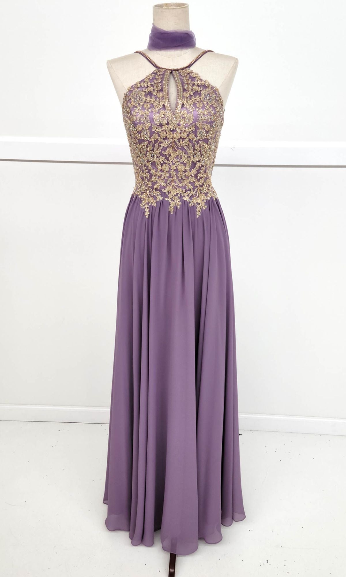 The High-Neck Long A-Line Prom Dress: Chicas C1521 is a sleeveless lavender gown with golden lace embroidered bodice, keyhole neckline, flowing skirt, and matching choker displayed on a mannequin.