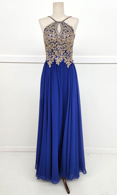 The Chicas C1521 High-Neck Long A-Line Prom Dress features a sleeveless royal blue design with gold lace embroidery, a keyhole neckline, and a flowing chiffon skirt, beautifully showcased on a dress form.