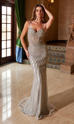 A woman in a fitted, silver Beaded Long Glitter Prom Dress: Nox Anabel C1608 stands indoors on a marble floor near a staircase and a window with green curtains.