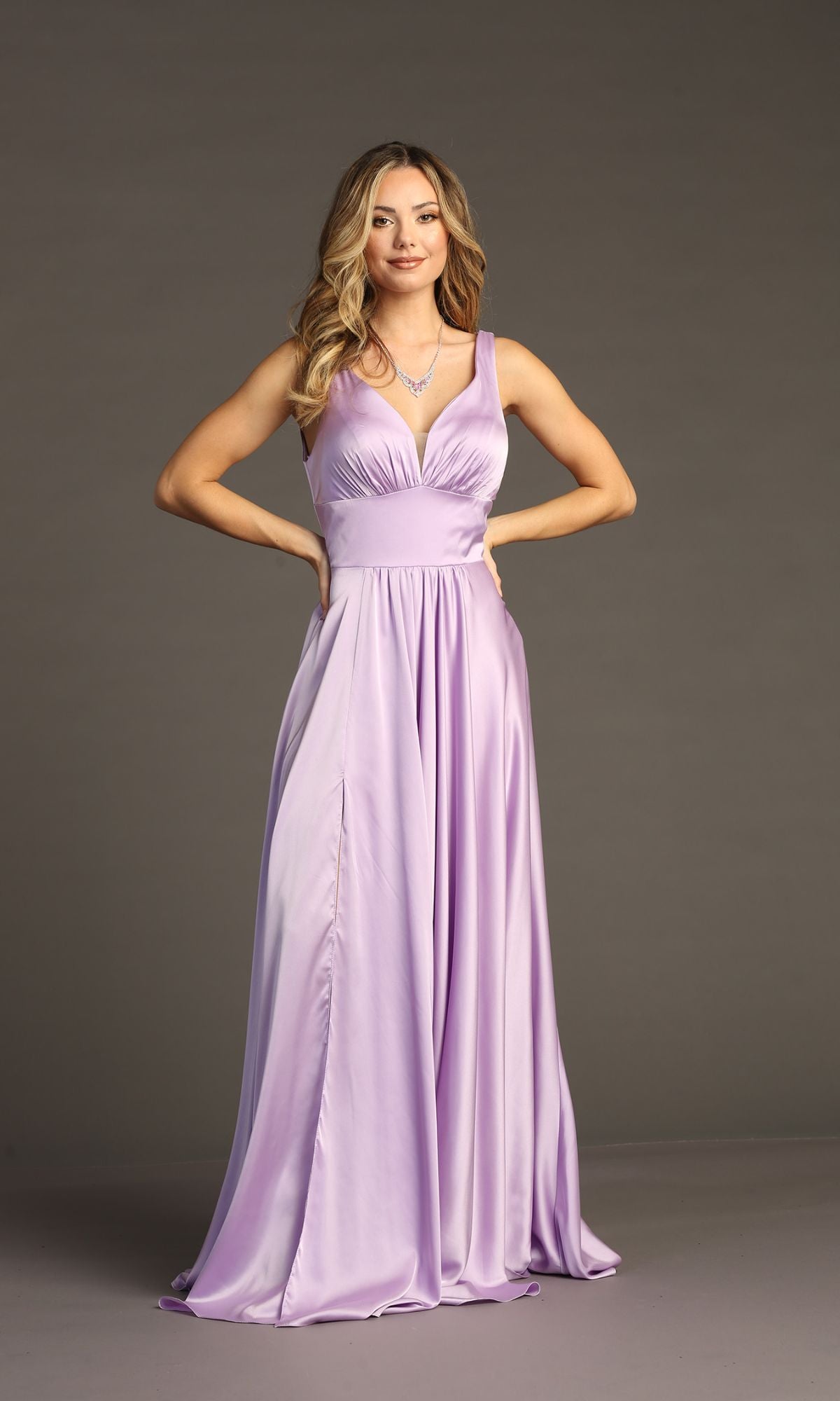 Woman stands with hands on hips, wearing the Chicas C242 Empire-Waist Long A-Line Prom Dress—a sleeveless lavender satin gown with V-neckline—posing against a plain gray background.