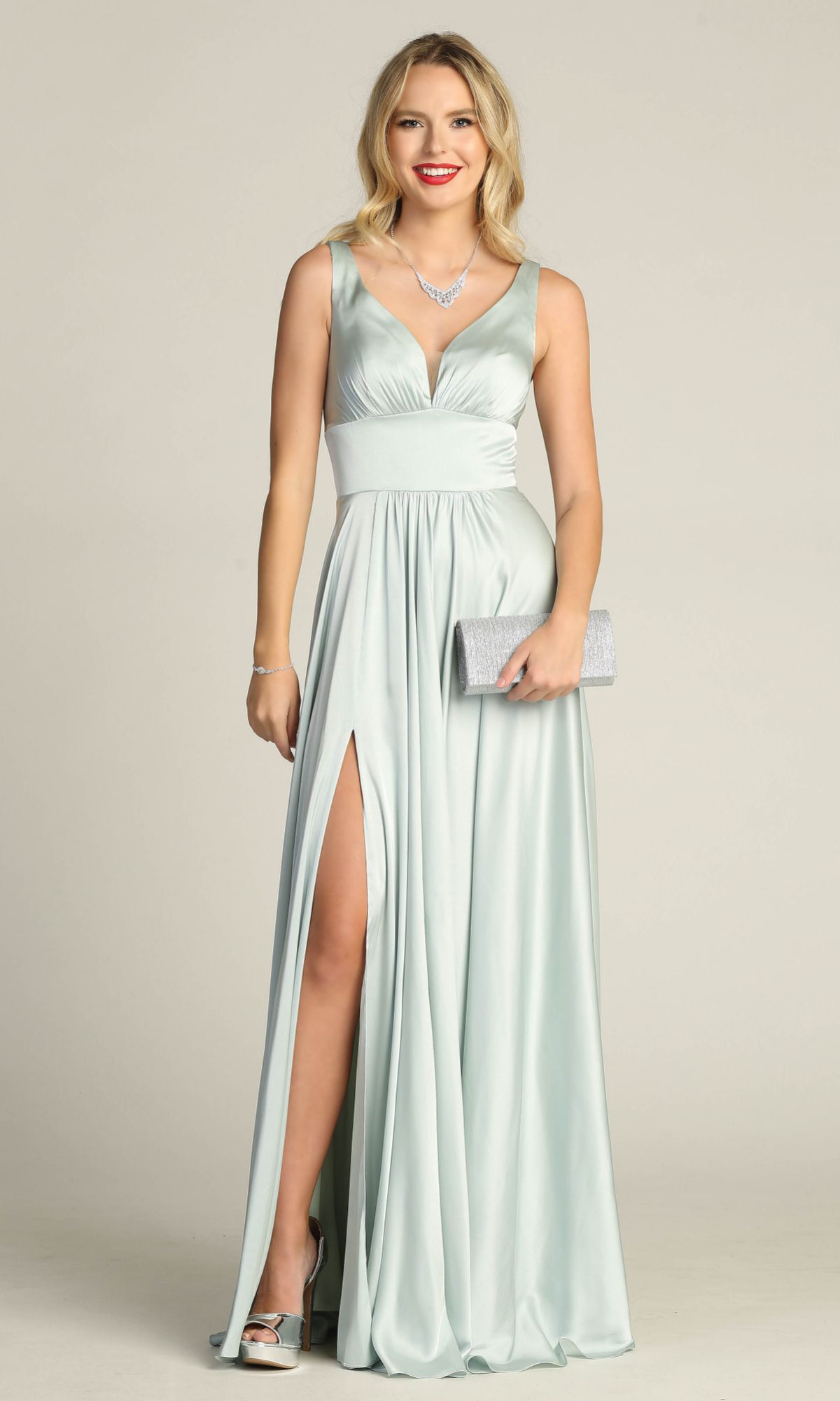 A woman wearing the Empire-Waist Long A-Line Prom Dress: Chicas C242—a light blue sleeveless gown with a deep V-neck and thigh-high slit—paired with silver heels and clutch for an elegant formal look.