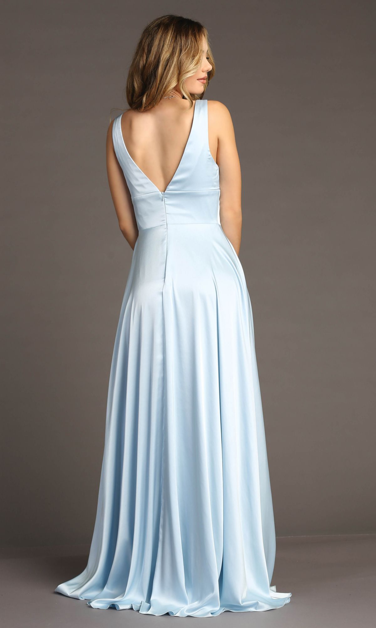 A woman, seen from behind, wears the Empire-Waist Long A-Line Prom Dress: Chicas C242— a floor-length light blue satin gown with a deep V-back, set against a plain gray background.