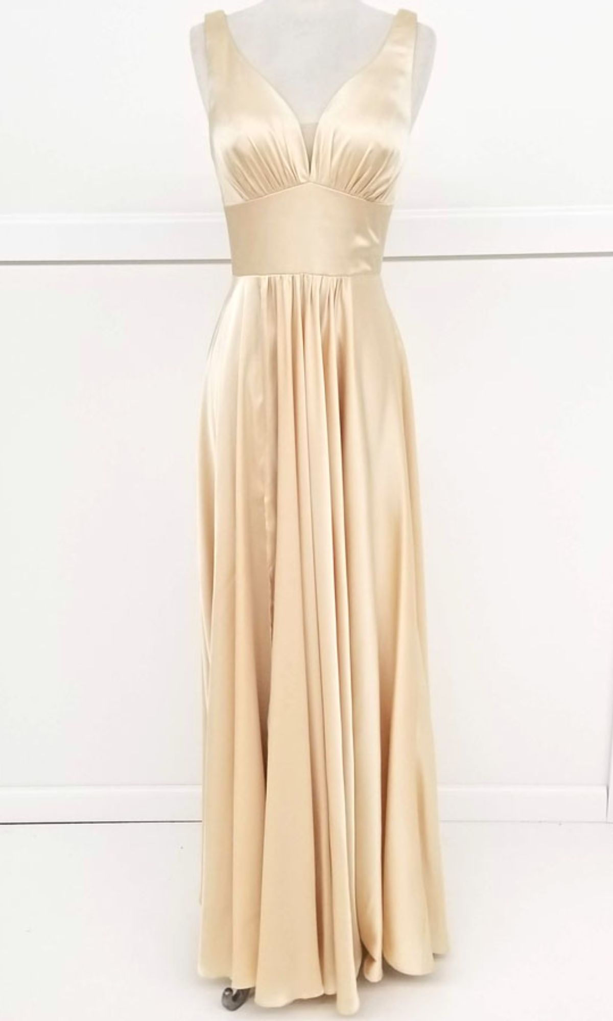 The Empire-Waist Long A-Line Prom Dress: Chicas C242 is a sleeveless, floor-length satin gown in light champagne with a V-neckline and fitted waistband, exuding timeless elegance on display.