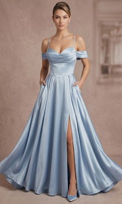 A woman stands in front of a plain background wearing the Long Prom Dress: Chicas C2575 in blue, featuring off-shoulder sleeves, a thigh-high slit, and a flowing A-line skirt, with matching heels completing her elegant look.