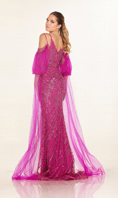 A woman stands facing backward, wearing the Cecilia Couture C270 long formal dress in fuchsia with sparkly embellishments and sheer cape-style sleeves, set against a plain light background.