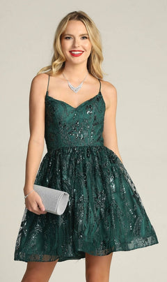 A woman wearing the Lace-Up Glitter-Print Short Homecoming Dress C317 in dark green, with thin straps and a sleeveless design, holds a silver clutch and wears a silver necklace against a plain background.