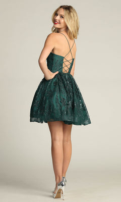Wearing the Lace-Up Glitter-Print Short Homecoming Dress C317, a woman stands in silver heels with a playful A-line skirt and glitter details, facing away but glancing over her shoulder.