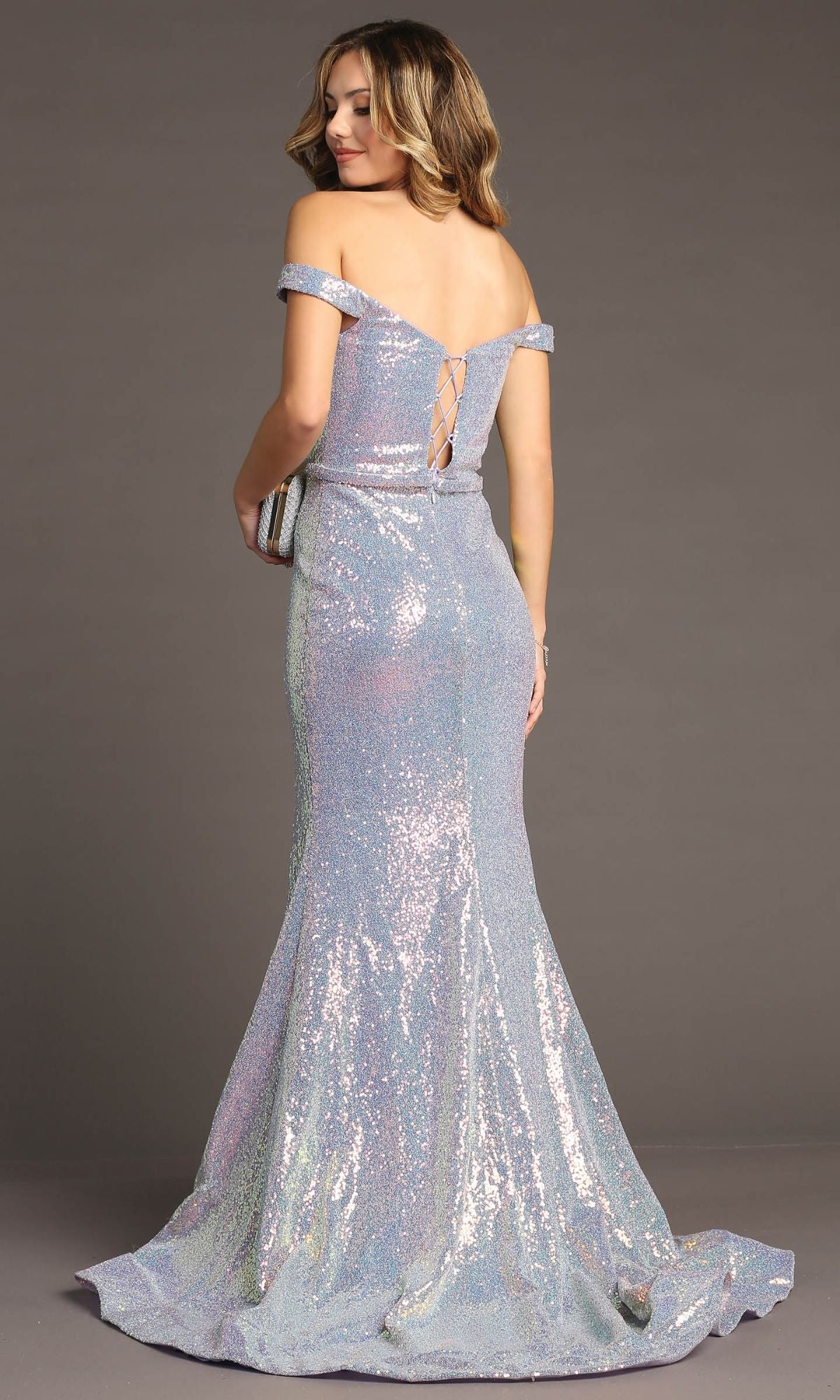 A woman in the Chicas C324 Off-Shoulder Long Sequin Prom Dress stands facing away, holding a clutch. This floor-length dress features iridescent sequins and lace-up back detailing for an elegant evening look.