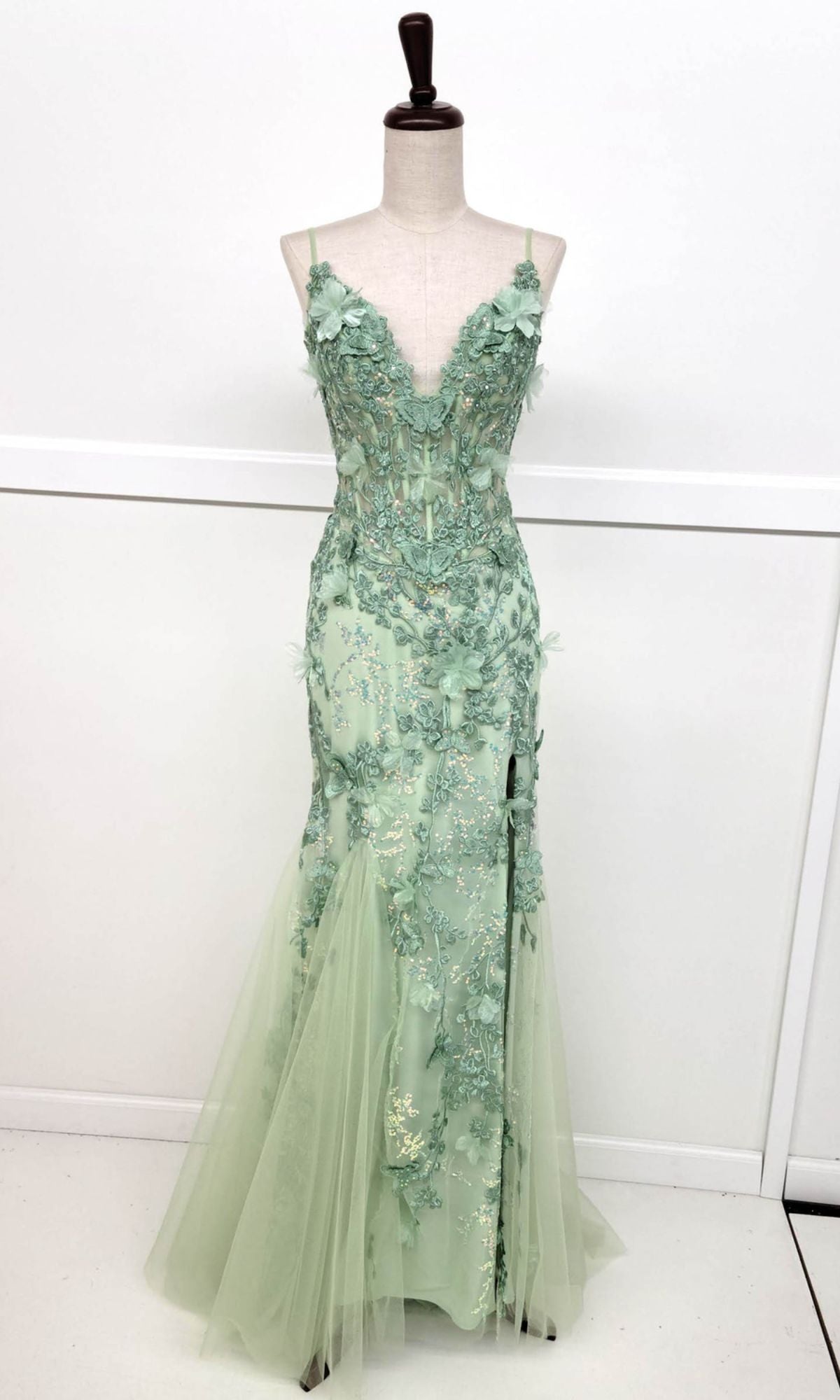 A mannequin showcases the Chicas C328 Floral-Embroidered Long Prom Dress, a sleeveless mint green gown with floral appliqué, deep V-neckline, and a flowing floor-length tulle skirt.