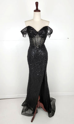 The Off-Shoulder Long Sequin Prom Dress: Chicas C331 features black sequins, sheer accents, and a front slit. Displayed on a dress form with a plain background, it’s perfect for anyone seeking an elegant evening gown.