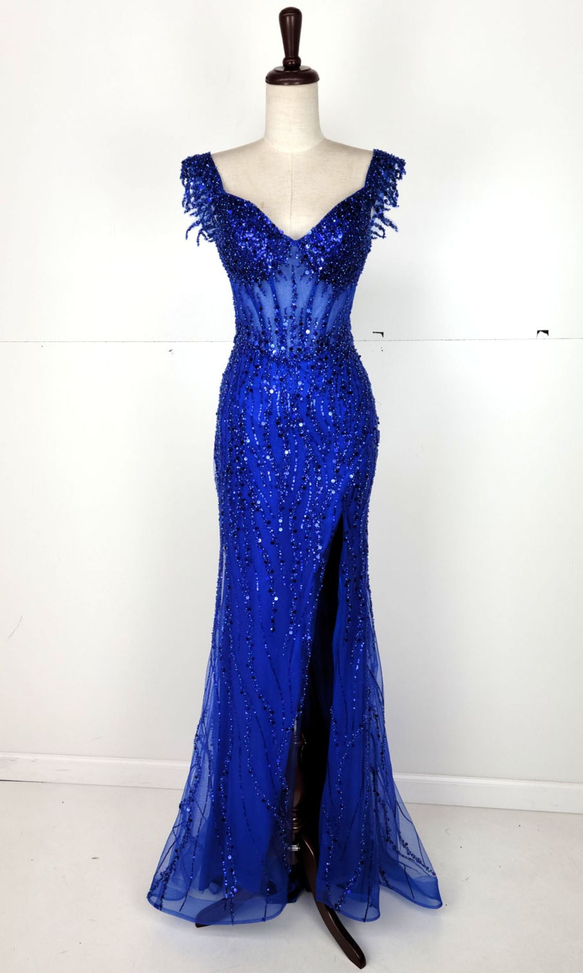 The Off-Shoulder Long Sequin Prom Dress: Chicas C331 is shown on a dress form against a plain white background, featuring royal blue sequins, off-the-shoulder straps, a sweetheart neckline, and a front slit.