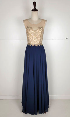 The Embroidered-Bodice Long Prom Dress: Chicas C3320 features a sleeveless sheer beige bodice with gold embroidery and a flowing dark blue A-line skirt, shown on a dress form against a plain background.