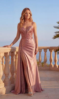 A woman stands on a stone terrace in the Sheer-Waist Long Satin Prom Dress: Chicas C342, which features lace details, a beaded bodice, and a thigh-high slit; palm trees and sky are visible behind her.