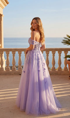 Wearing the Long Prom Dress: Chicas C350, a woman in a light purple glitter tulle ball gown with a corset bodice stands on a balcony overlooking the sea, her body turned slightly to the side.