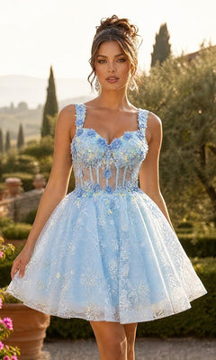 A woman stands outdoors in a garden setting, wearing the Chicas C352 short homecoming dress in Bahama Blue, featuring a fit-and-flare silhouette with 3D floral appliques and a sheer bodice.