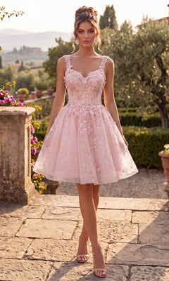A woman stands on a stone path in a lush garden setting, wearing the Chicas C372 Short Homecoming Dress in blush—a knee-length, sleeveless dress featuring delicate floral details and a flattering fit-and-flare silhouette.