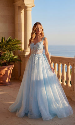 A woman in the sky blue Long Prom Dress: Chicas C379 with a flowing silhouette and floral details stands on a balcony overlooking the sea.