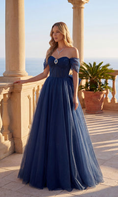A woman in the Chicas C386 Long Prom Dress in navy stands on a stone balcony with columns, overlooking the ocean.