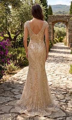 A woman in the Chicas C389 Long Formal Dress, featuring sparkling embellishments and a mermaid silhouette, stands on a stone path in a garden with her back to the camera.