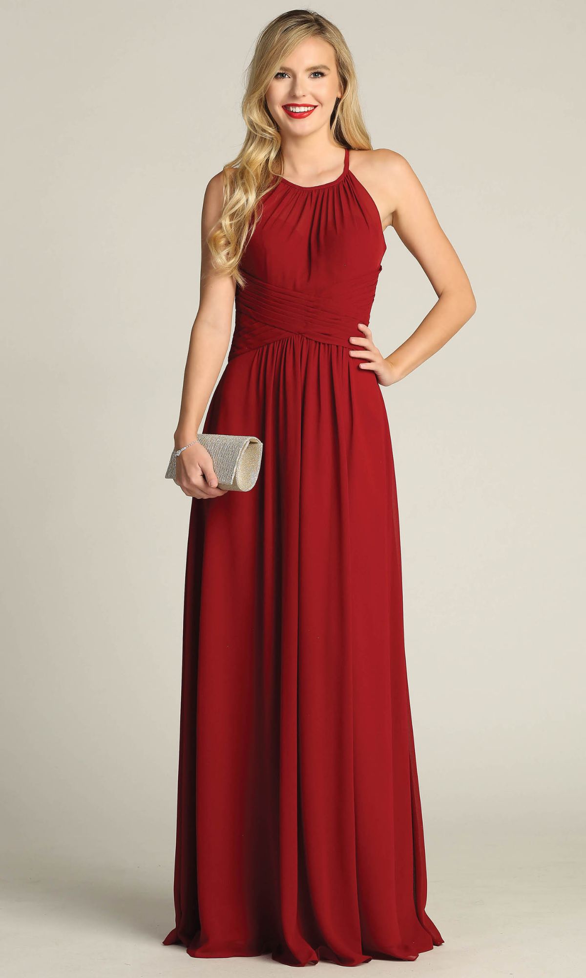A woman stands against a plain background wearing the Chicas C5150 high-neck, sleeveless, floor-length A-line prom dress in red and holding a silver clutch.