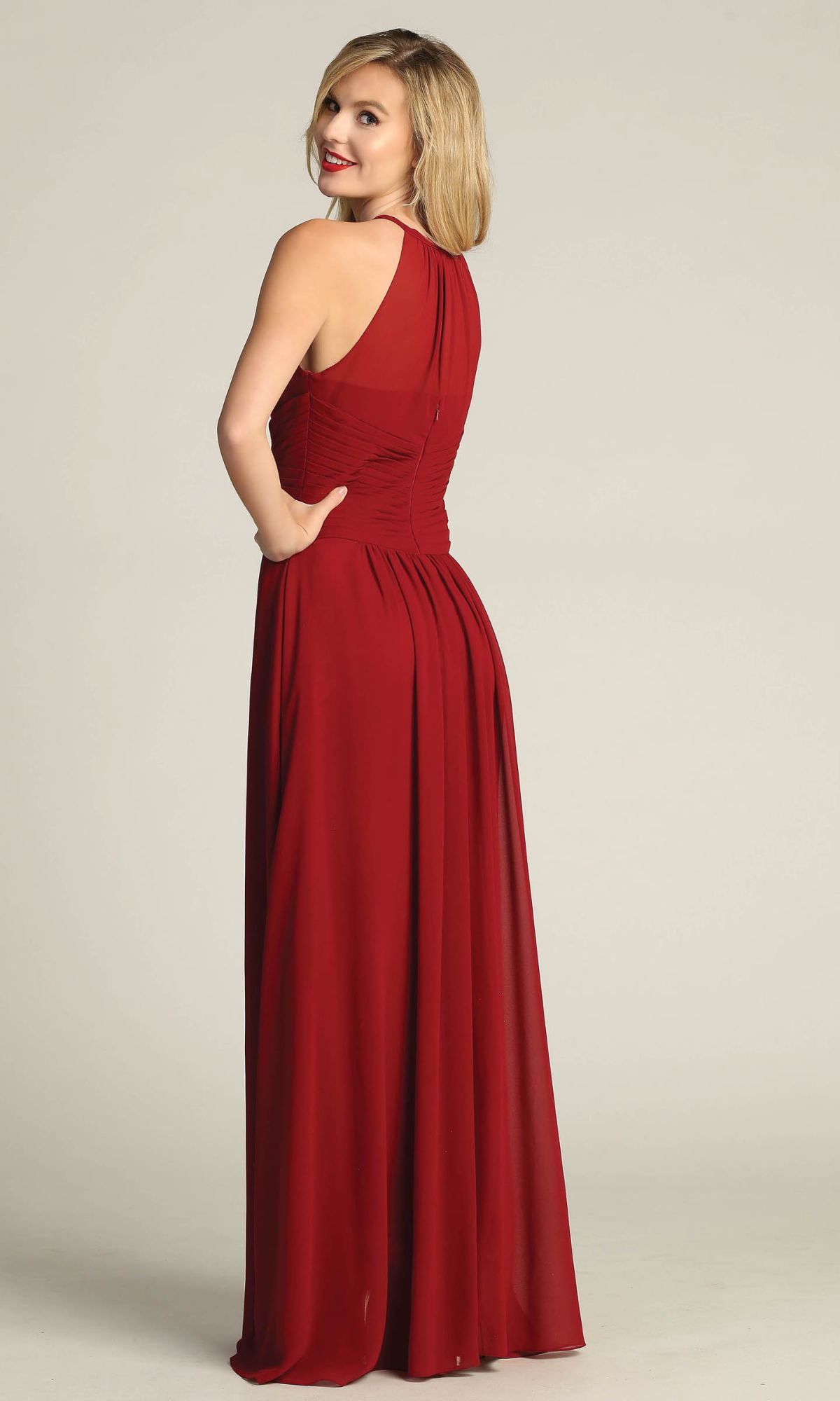 A woman in the Chicas C5150 High-Neck Long A-Line Prom Dress—an affordable, sleeveless, floor-length red gown—stands turned slightly to the side, smiling over her shoulder.
