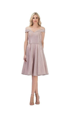A woman wearing the blush Short Homecoming Dress: Chicas C7518, which features a knee-length sparkly design and an off-the-shoulder neckline, paired with high-heeled sandals, stands against a plain white background.