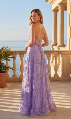 A woman stands on a sunlit terrace overlooking the ocean, wearing the Chicas C804 long prom dress in lavender with floral lace embroidery and a lace-up back.