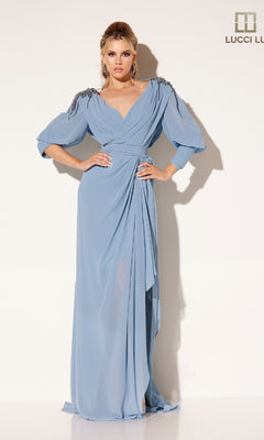 A woman poses in the Lucci Lu C8092 long formal dress, featuring floor-length draped light blue fabric, embellished shoulders, and long sleeves, set against a plain white background.