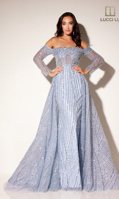 A woman stands against a plain background wearing the Lucci Lu C8112, a light blue long formal dress with an off-the-shoulder bodice, sheer long sleeves, sparkling sequin embellishments, and an elegant A-line overskirt.