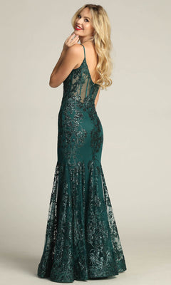 Woman wearing the Chicas C813 Long Glitter-Print Prom Dress, a dark green, sleeveless, floor-length mermaid gown with a sheer back panel, smiles over her shoulder.