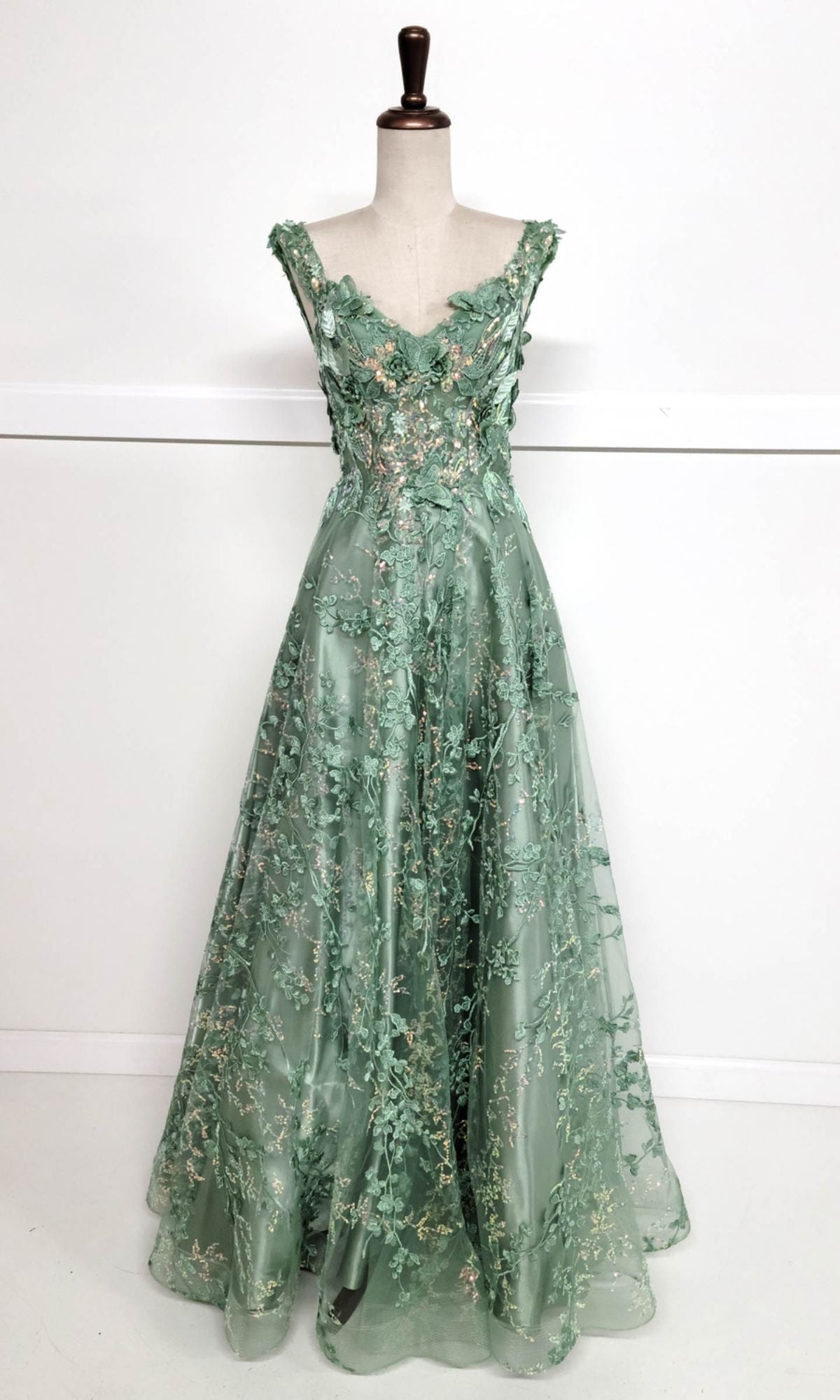 The Floral-Print Lace-Up Long Prom Dress: Chicas C818 is a sleeveless green gown with a corset-style bodice and delicate floral embroidery, shown on a dress form against a plain white background.