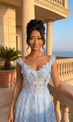A woman in the Floral-Print Lace-Up Long Prom Dress: Chicas C818 stands on a balcony with stone columns, gazing at the ocean and sky in the background.