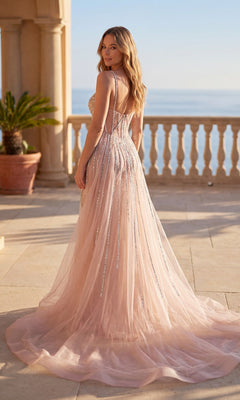 A woman stands on a sunlit seaside terrace in the Chicas C824 Long Prom Dress, featuring light pink beads, jewel rhinestones, and a delicate tulle overskirt as her floor-length gown catches the light.